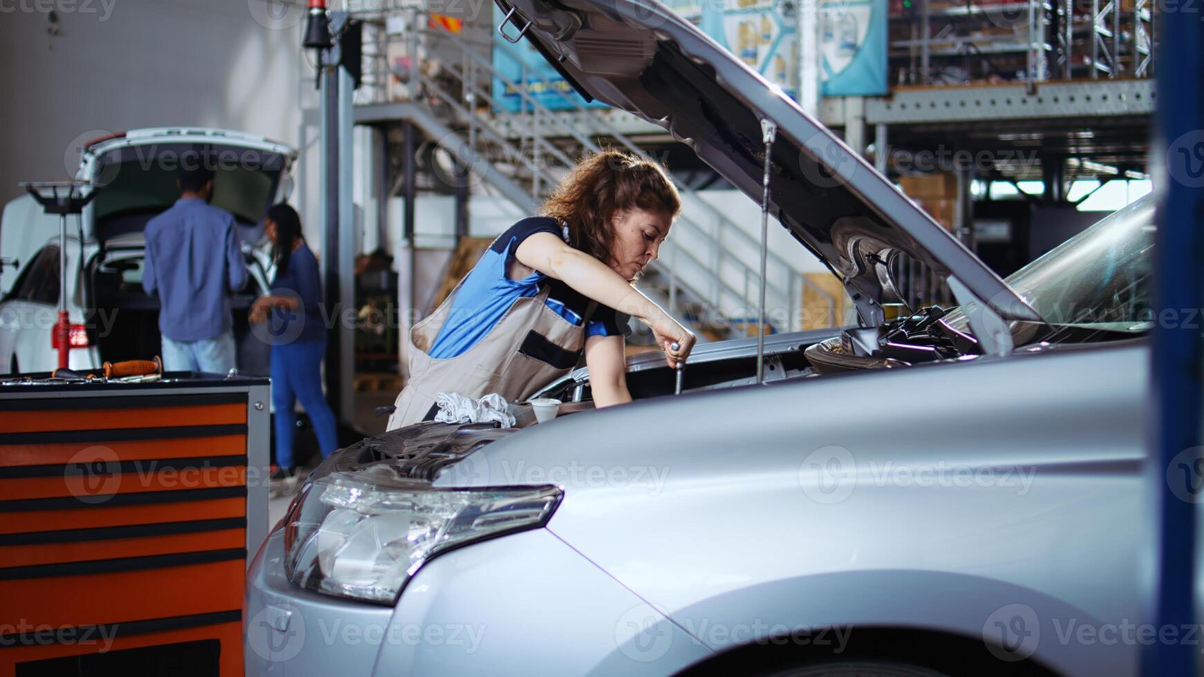 Certified serviceman in garage finishing fixing car for customer, removing remaining oil leaks inside vehicle. Professional does thorough parts cleaning on client automobile in repair shop photo