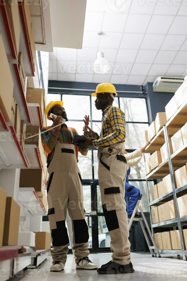 Warehouse employees talking with stock supply chain manager on landline phone. Retail storehouse employees discussing goods order on telephone and giving inventory information photo