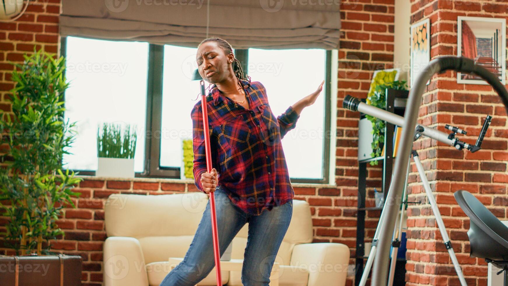 hembra adulto bailando y teniendo divertido limpieza familiar, escuchando a música y haciendo danza se mueve en vivo habitación. moderno ama de casa disfrutando Lavado de madera pisos con fregar. Mano disparo. foto