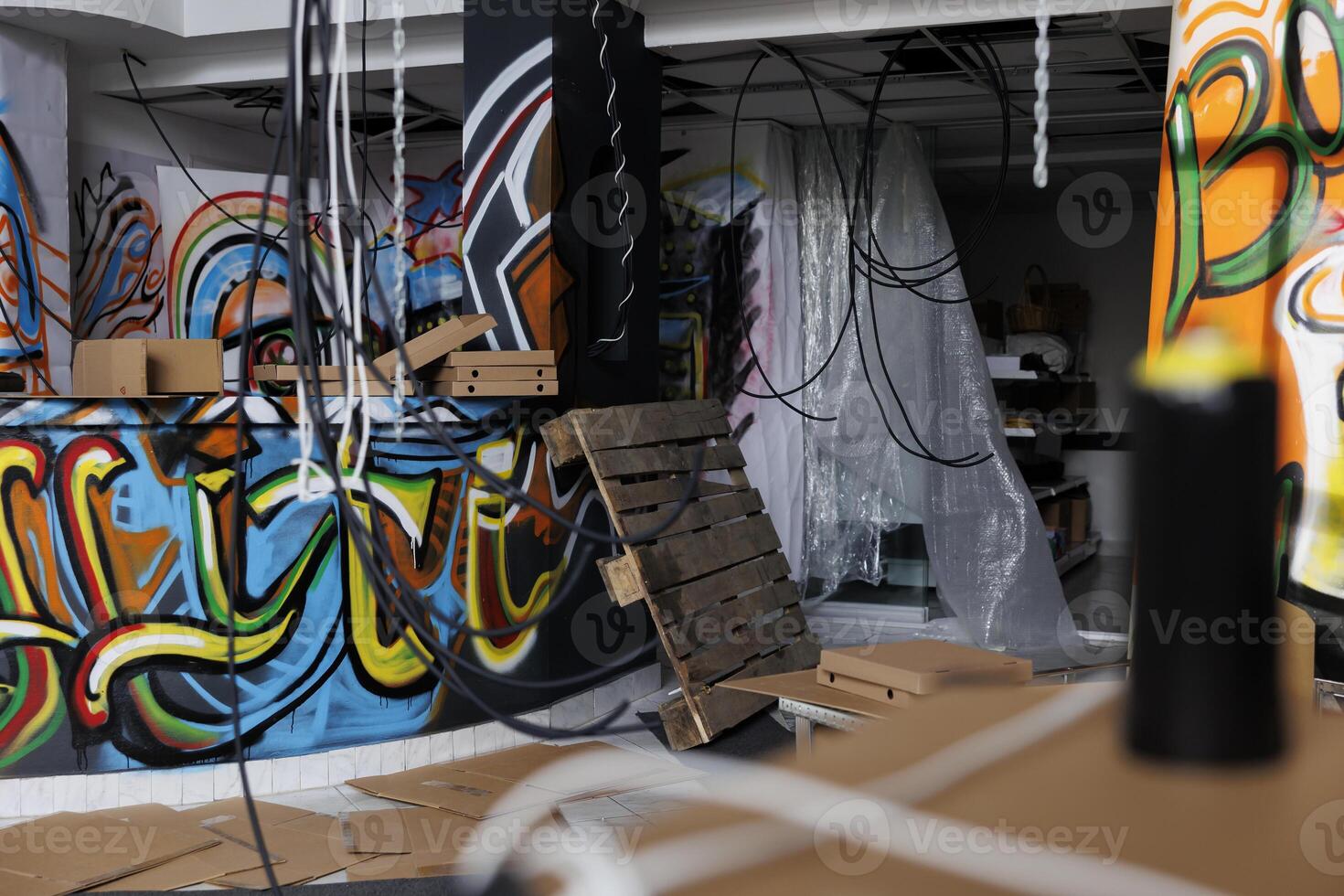 Empty neglected warehouse filled with wreck and rust, chaotic place with graffiti spray paint on dusty walls. Damaged structure of messy disintegrating building in crumbling abandoned state. photo