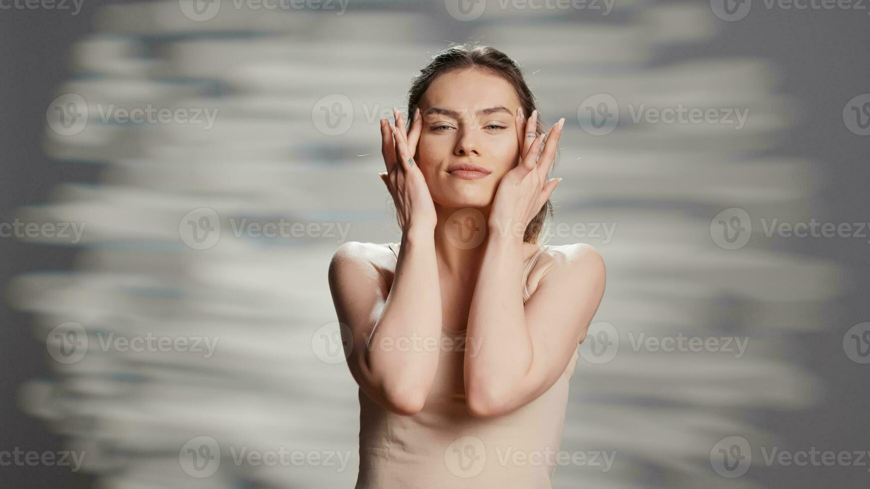 Confident woman using moisturizing facial cream for beauty routine, creating new ad campaign for glowing products. Cheerful sensual girl posing on camera to advertise nourishing luminous look. photo