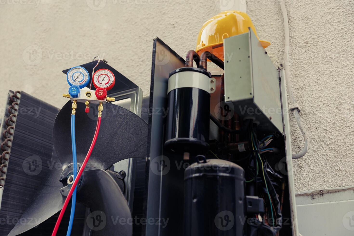 Out of order external air conditioner unit with protection cover removed in need of maintenance, with damaged electric internal parts. Outside HVAC system not operational anymore, ready to be serviced photo