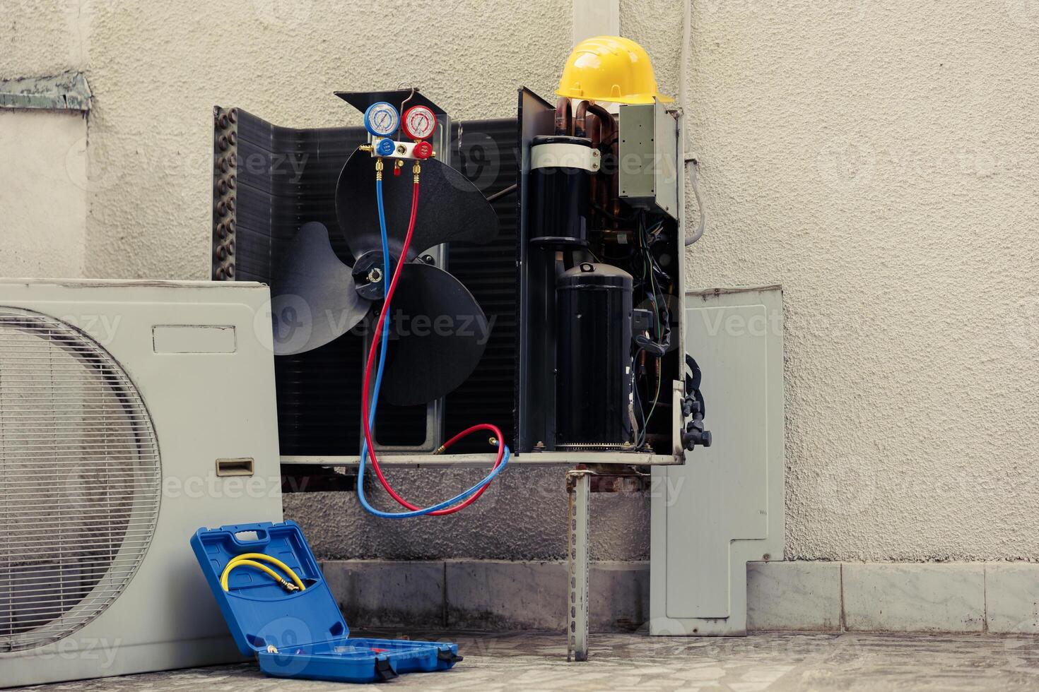 Broken external air conditioner unit with protection cover removed in need of repair, with damaged electric internal components and wiring. Outdoor HVAC system not working anymore, ready to be fixed photo