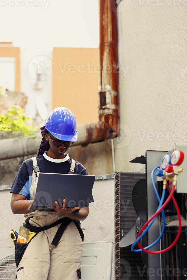 Engineer commissioned for routine expert maintenance to avoid costly servicing and ensure air conditioning systems longevity. Certified technician doing air conditioner probe, imputing data on laptop photo