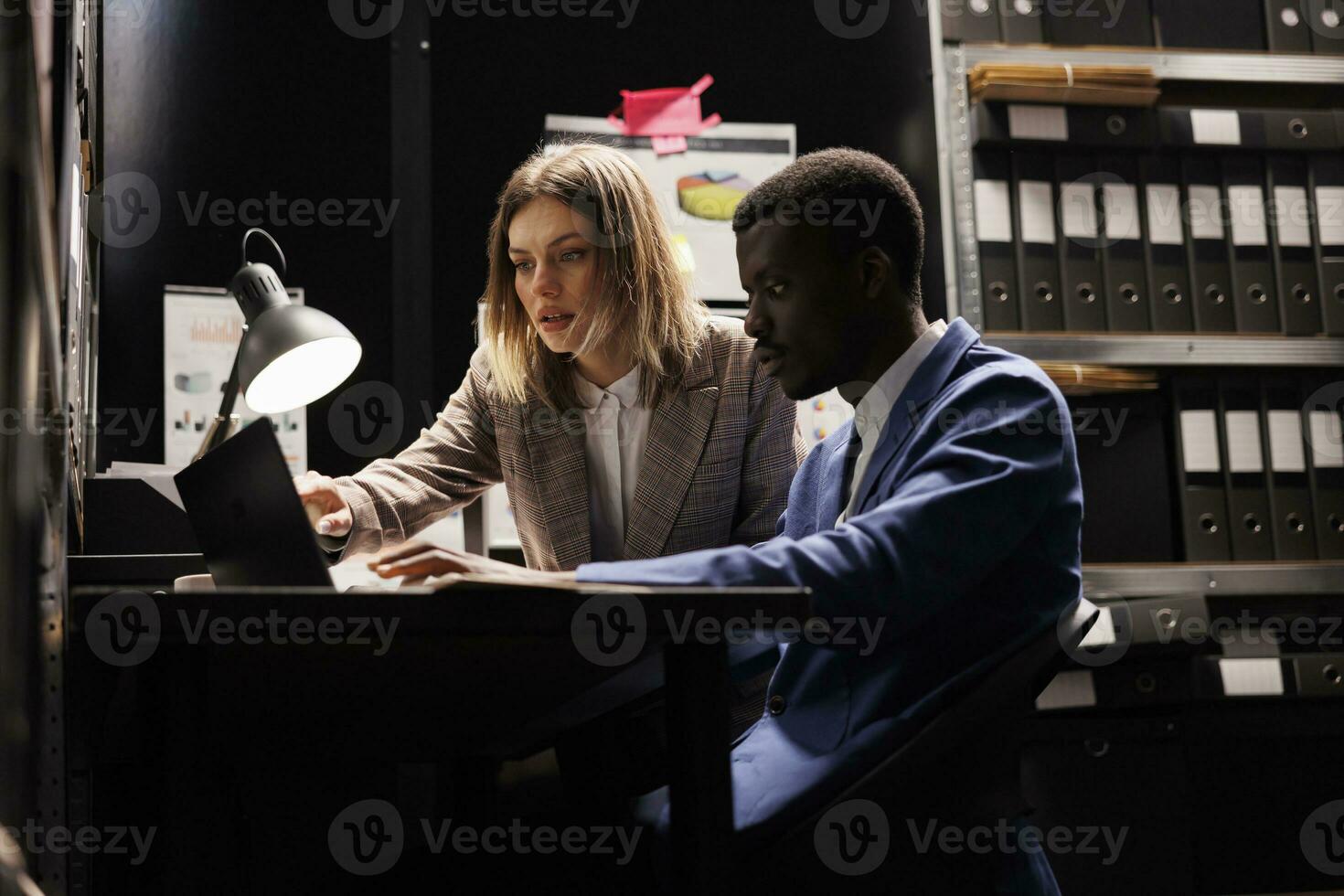 Management team discussing bureaucracy record, working overtime at accountancy report in storage room. Diverse bookkeepers analyzing administrative documents in corporate depository photo