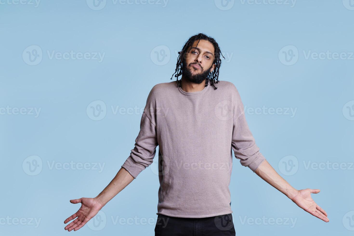 Puzzled arab man with hands spread in questioning gesture looking at camera and making unsure facial expression. Confused thoughtful person shrugging shoulders portrait photo