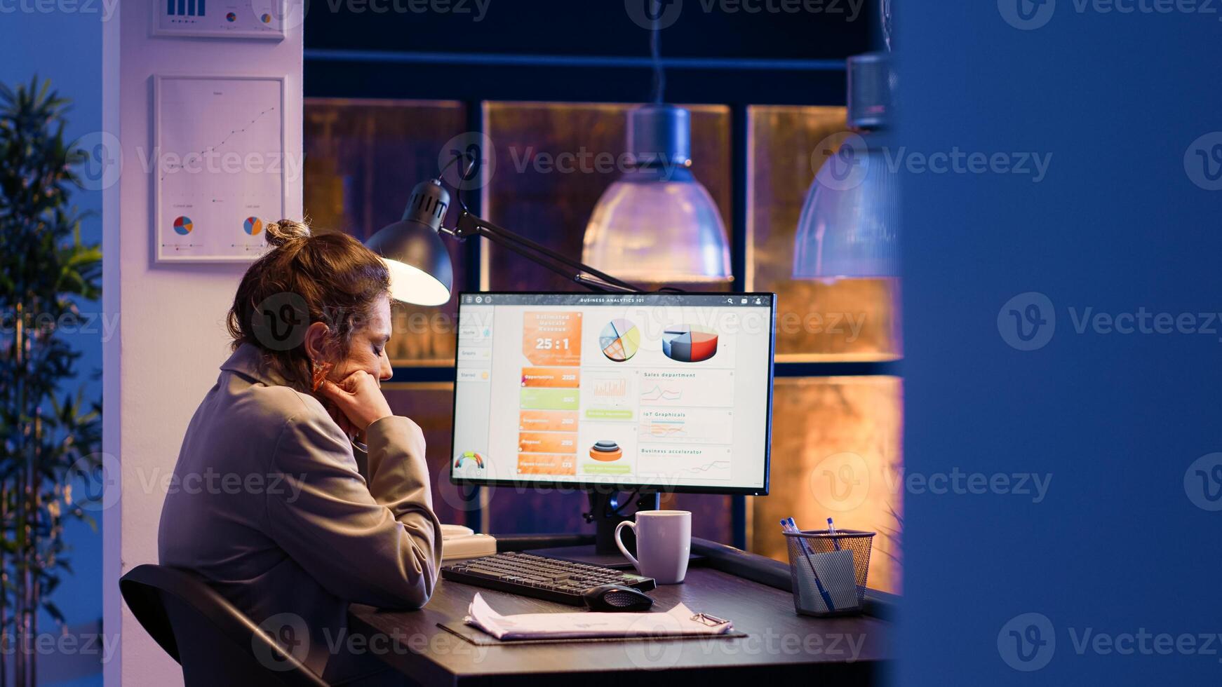 Young entrepreneur feeling sleepy in business office, working late on marketing strategy development. Startup manager yawning and being tired at job, planning financial statistics graphs. photo