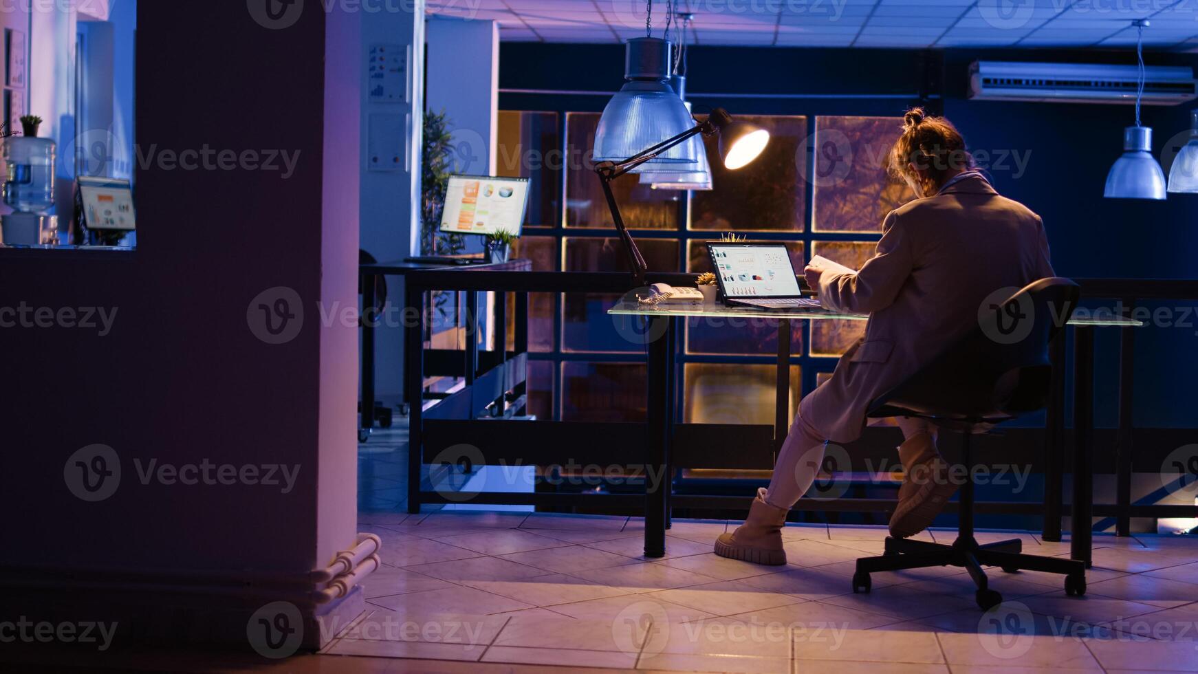 Advisor agent checking corporate report late at night, working overtime to develop new marketing strategy. Office manager planning financial graphs project on monitor. Handheld shot. photo