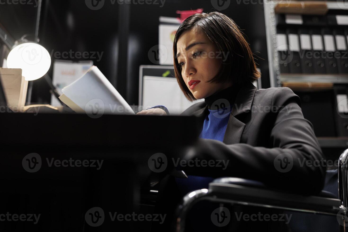 Paralyzed businesswoman executive in wheelchair checking accountancy budget plan data paperwork. Bureaucratic employee with disability in repository filled with document folders chart reports photo