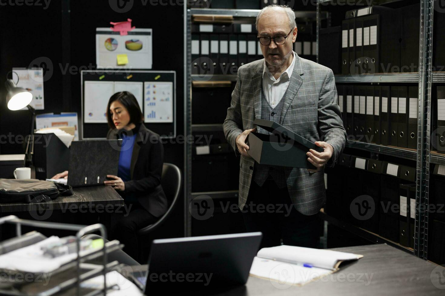 Senior manager bookkeeper storing annual profit revenue files before official business inspection. Bureaucratic workplace filled with flowcharts and document folders on depository cabinet shelves photo