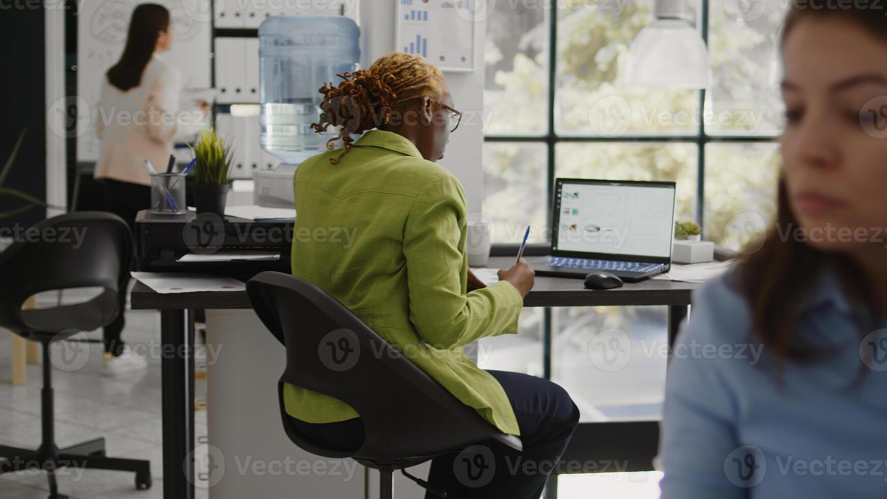 Business woman looking at annual report on laptop, planning corporate investment for marketing development. Startup worker checking data analytics on pc, taking notes on documents. photo