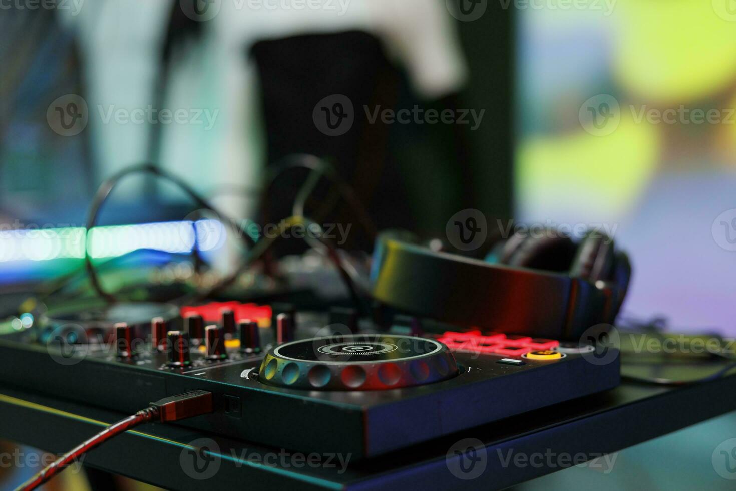 Dj controller with jog wheels, knobs and buttons for electronic music mixing at nightclub stage. Musician console panel and headphones for live performance in club close up photo