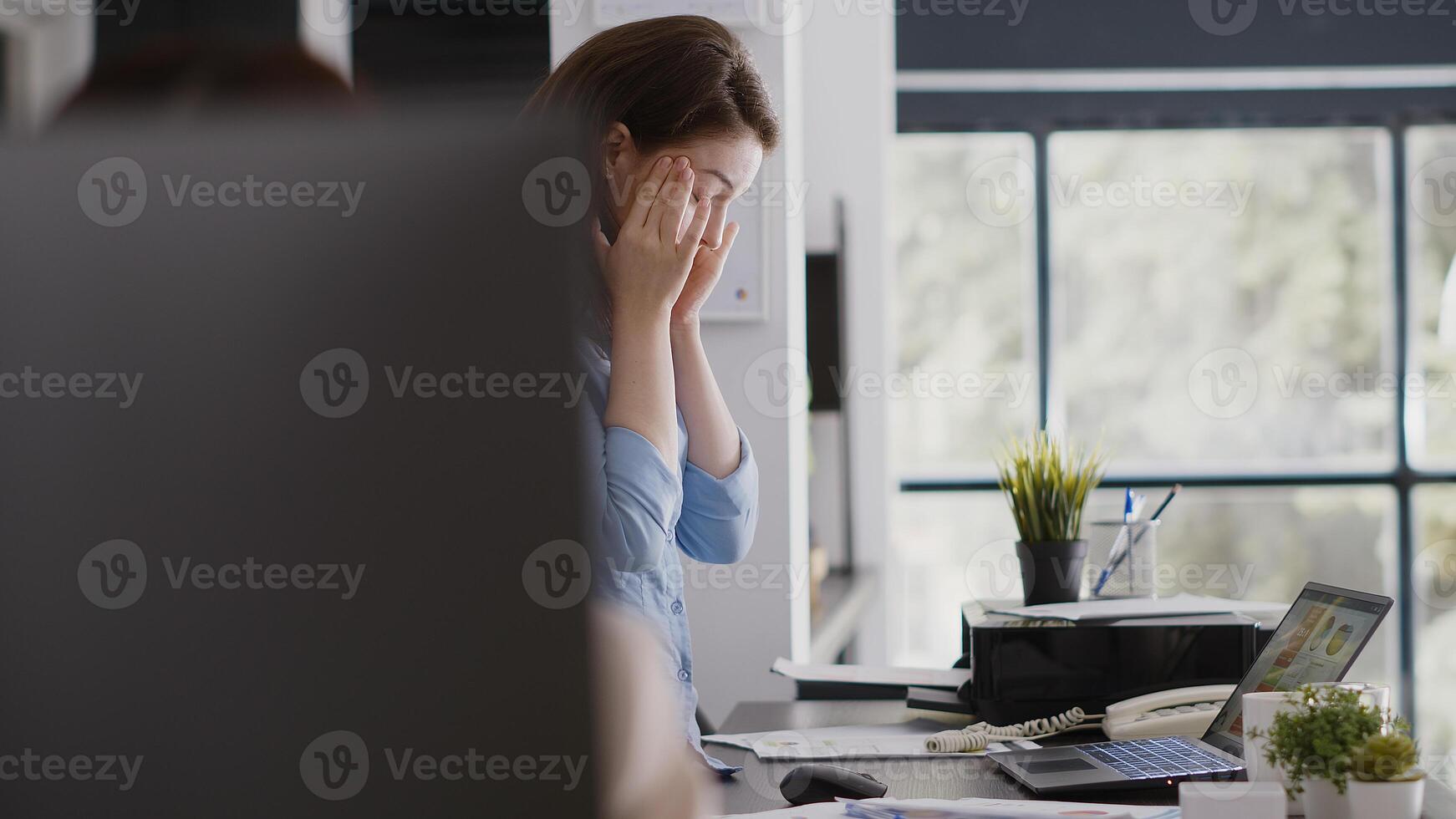 Office worker dealing with migraine and working on pc, rubbing temples and feeling stressed. Unhappy businesswoman having painful headache at job, work under pressure or in tension. photo