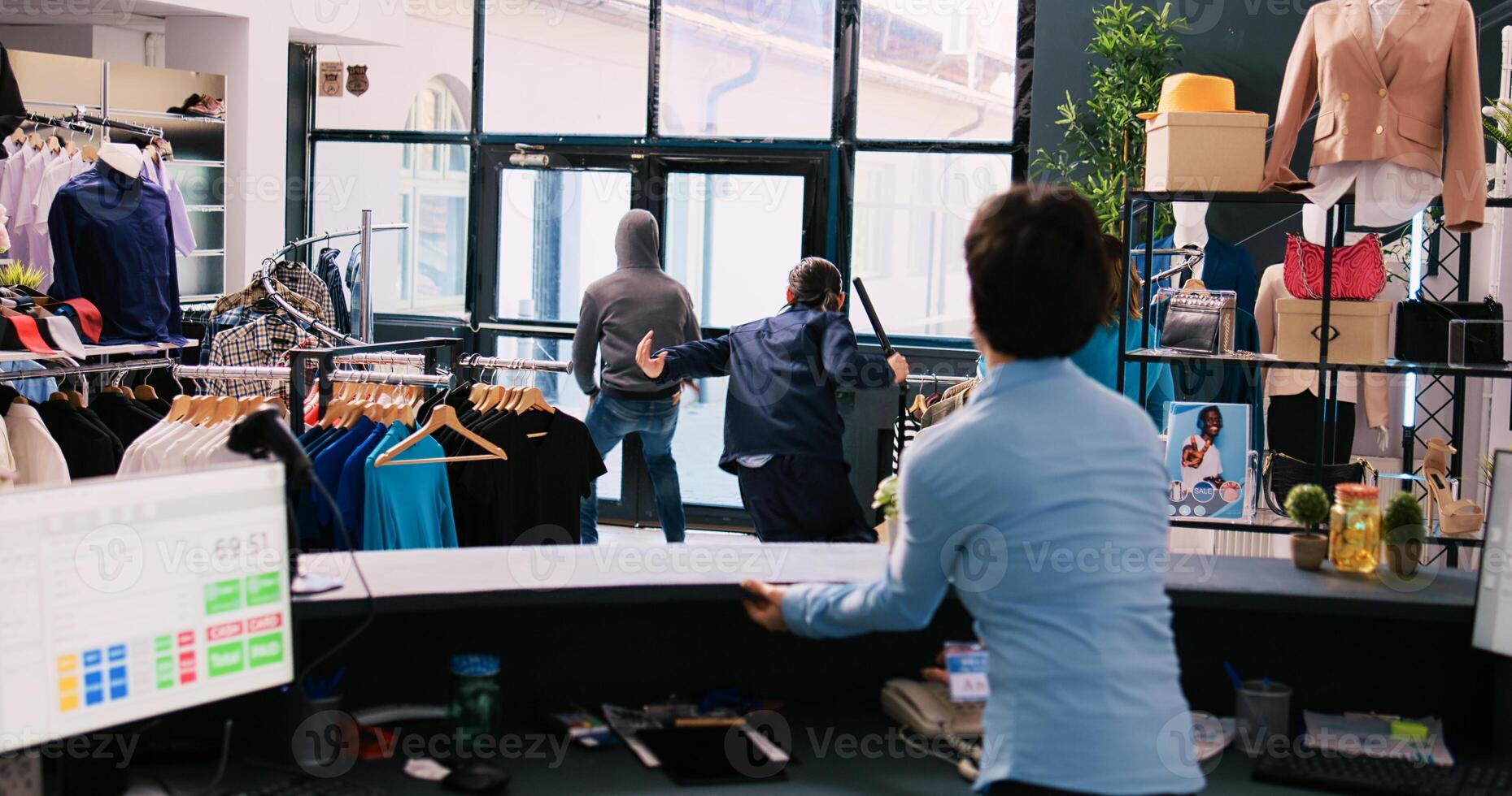 African american thief stealing trendy clothes, running from shopping centre. Asian bodyguard catches robber at store door, threatens him with the police in modern boutique. Burglary concept photo