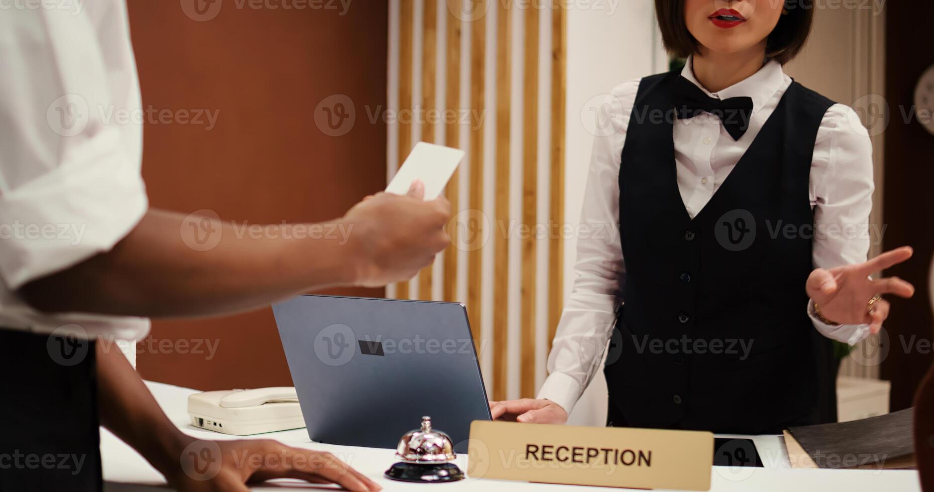 Asian receptionist offering african american business partners on work trip room access card key after finalizing check in. Tourists finishing booking process, close up dolly out shot photo