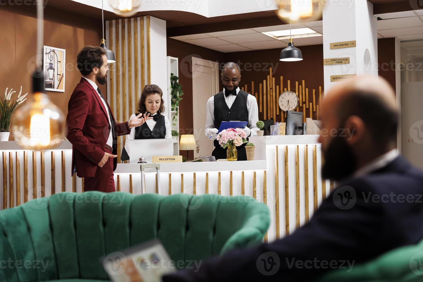 Guest asking hotel staff about services, ensuring pleasant stay and comfortable accommodation. Man travelling for work, employees providing great local recommendations after check in process. photo