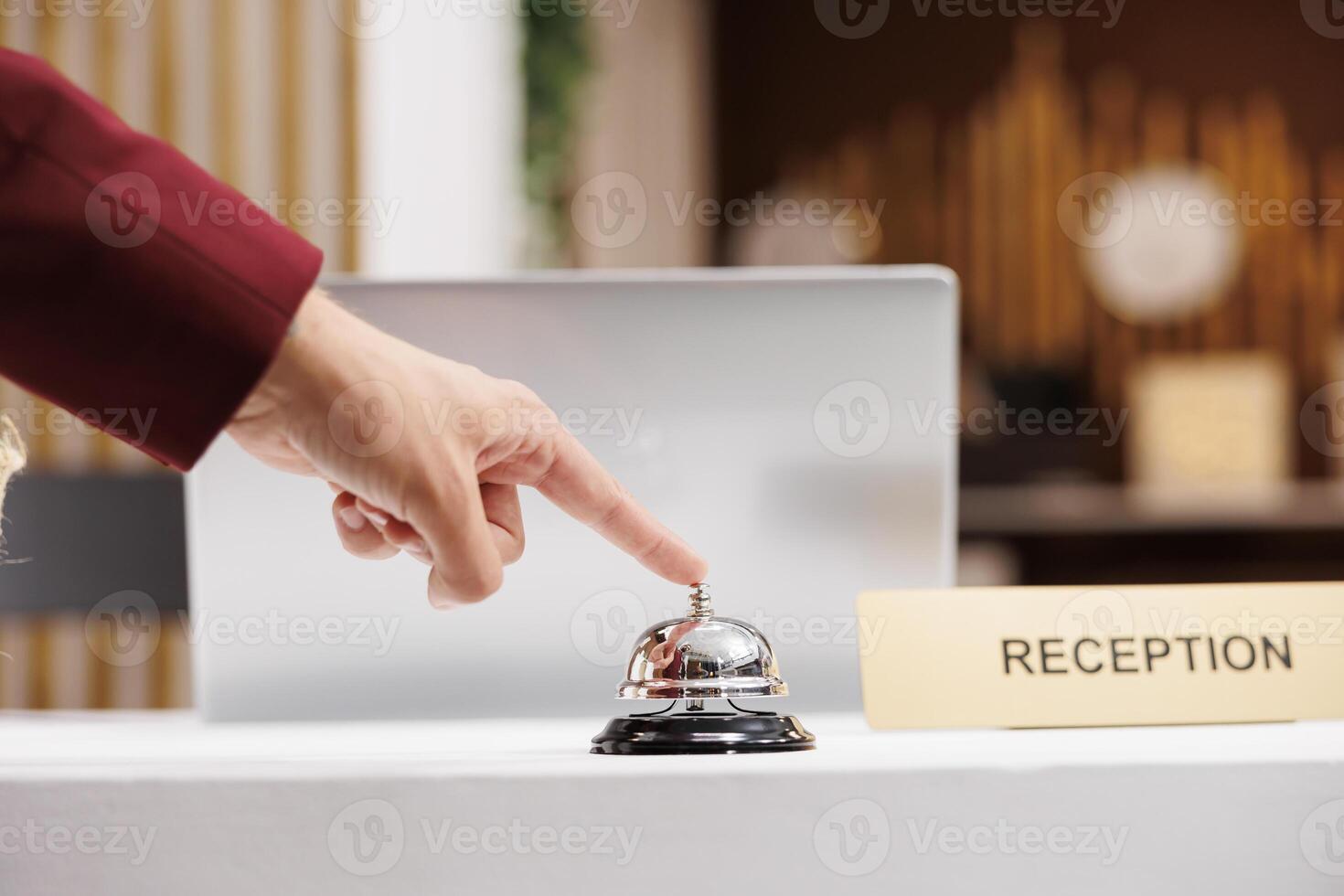 Guest using service bell at reception, ringing for assistance from front desk employees at hotel. Entrepreneur arriving in lobby and calling for receptionist, check in process. Close up. photo