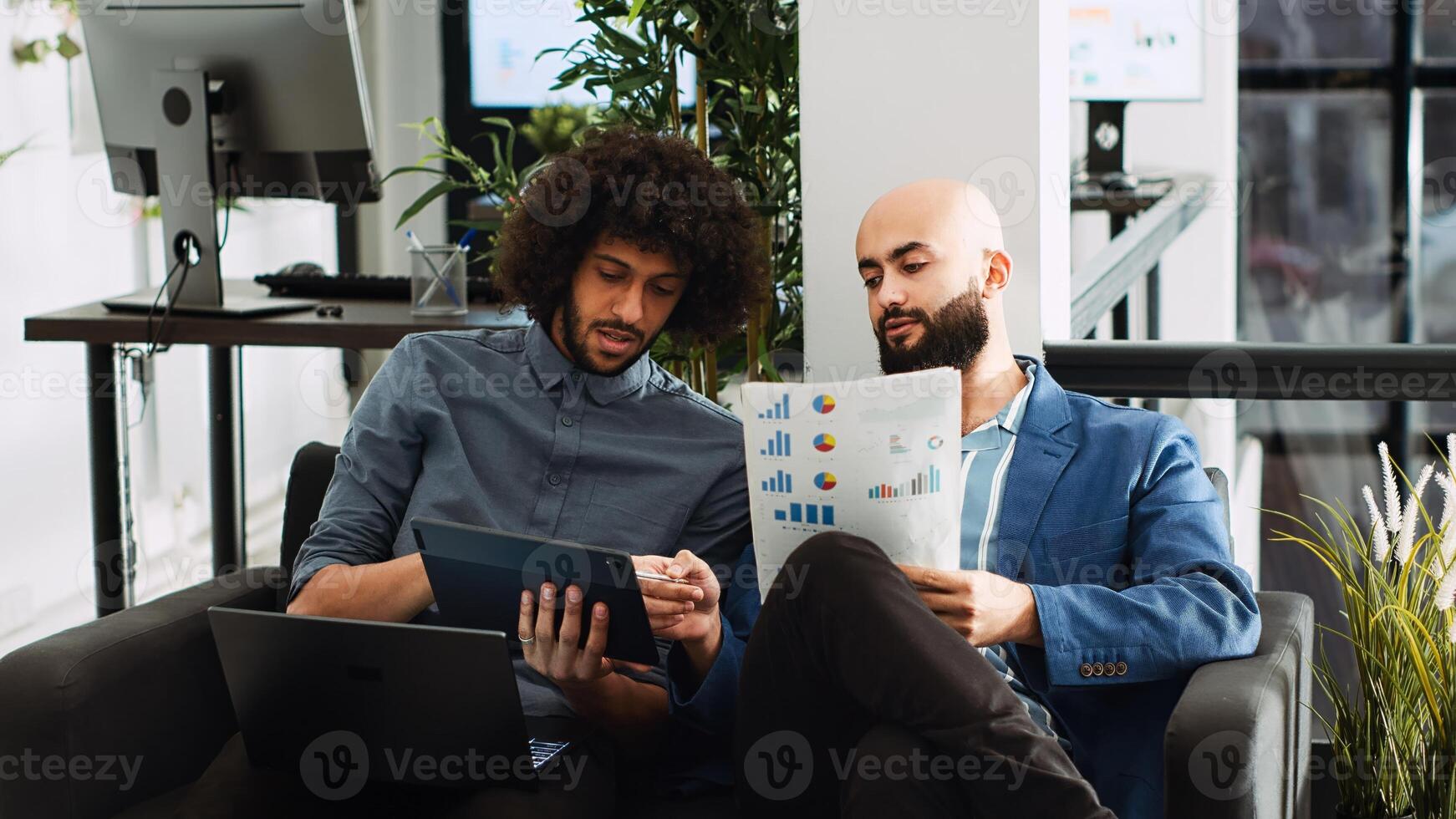 Colleagues review annual statistics in coworking space, analyzing data to create presentation for investment plan. Company workers collaborating on research for executive project. Handheld shot. photo