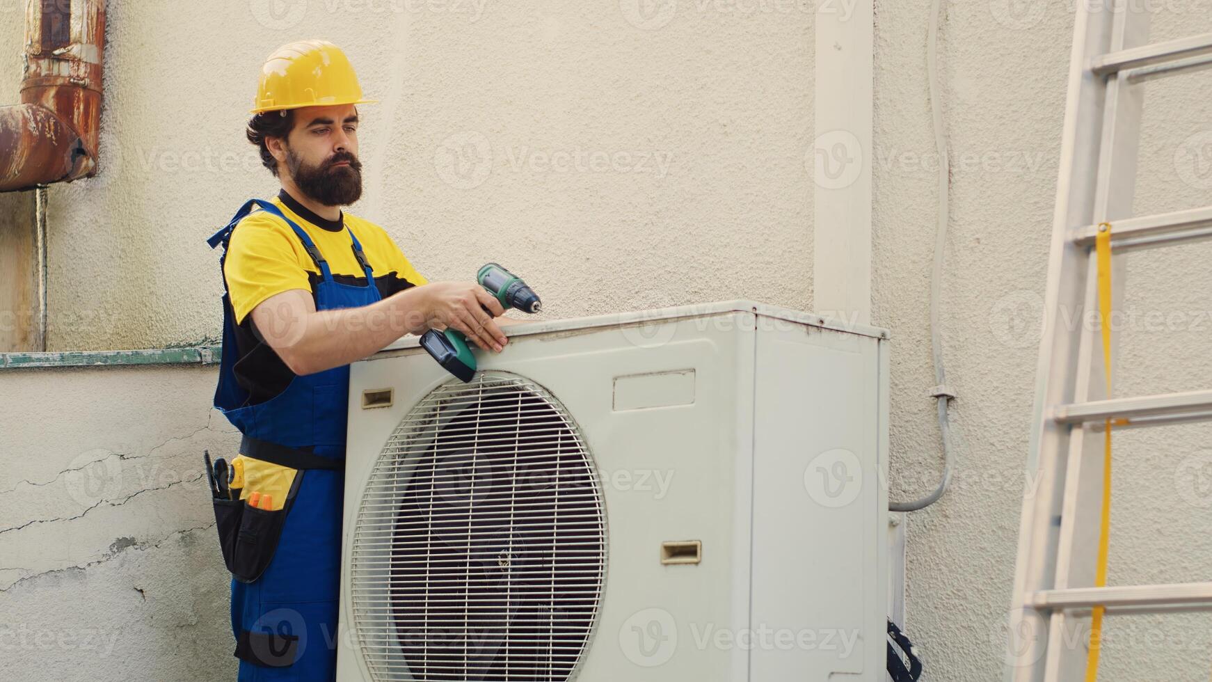 Knowleadgeable engineer dissasembling external air conditioner metal top coil panel to check for damaged components. Precise mechanic doing repairing on busted hvac system photo