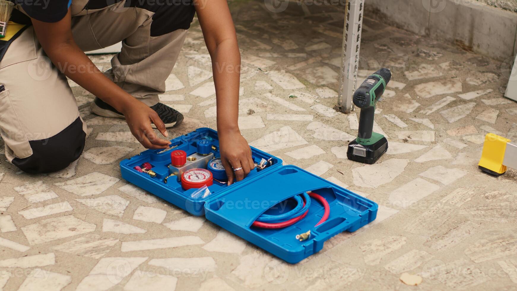 Competent mechanic unpacking toolkit with professional pressure measurement equipment needed to check freon levels. Proficient expert commissioned by client, preparing for HVAC system maintenance photo