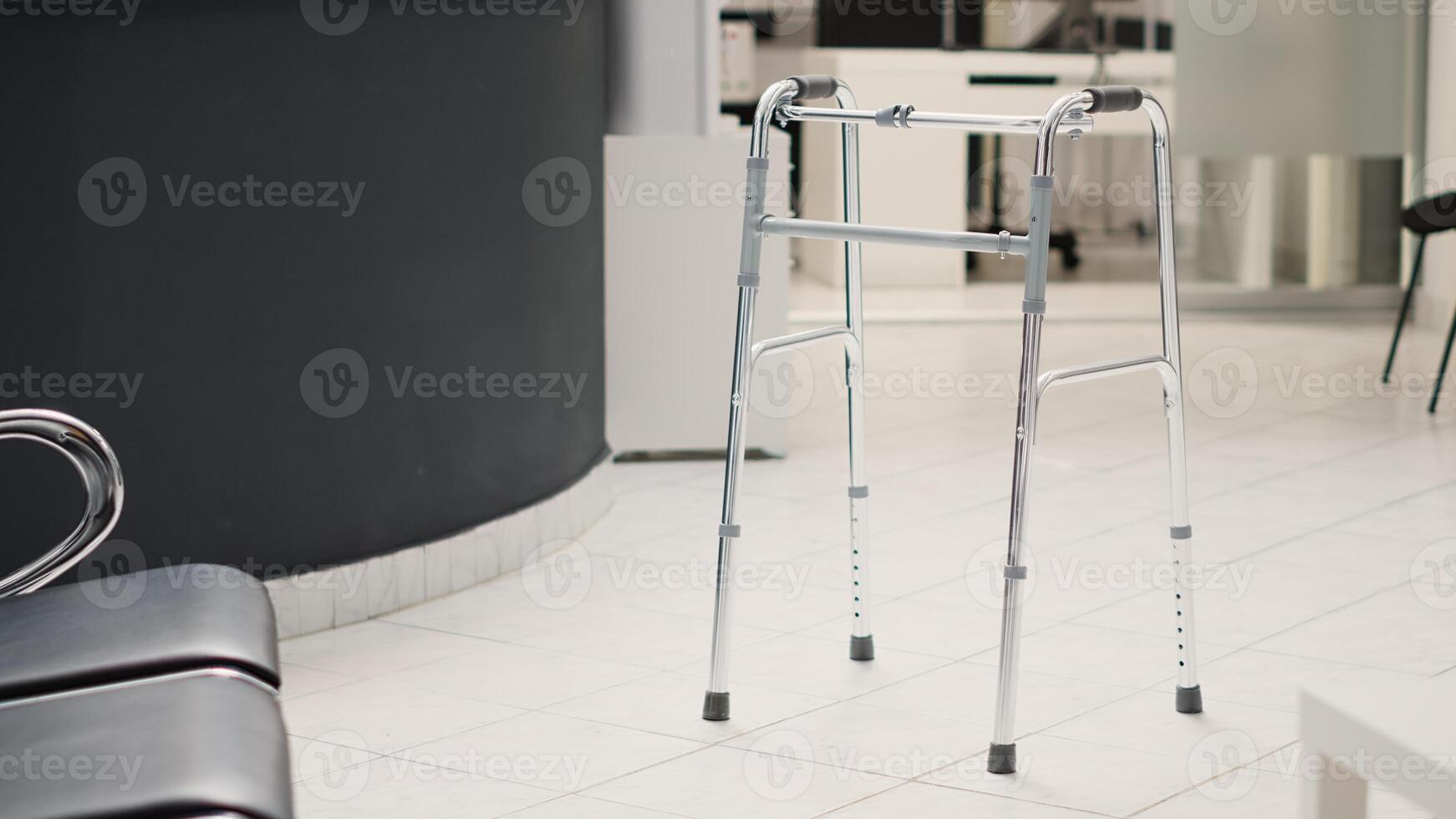 Diagnostic center with reception counter, walking frame placed in empty hospital lobby with registration front desk. Medical health care facility with chairs and consultation checkup. photo