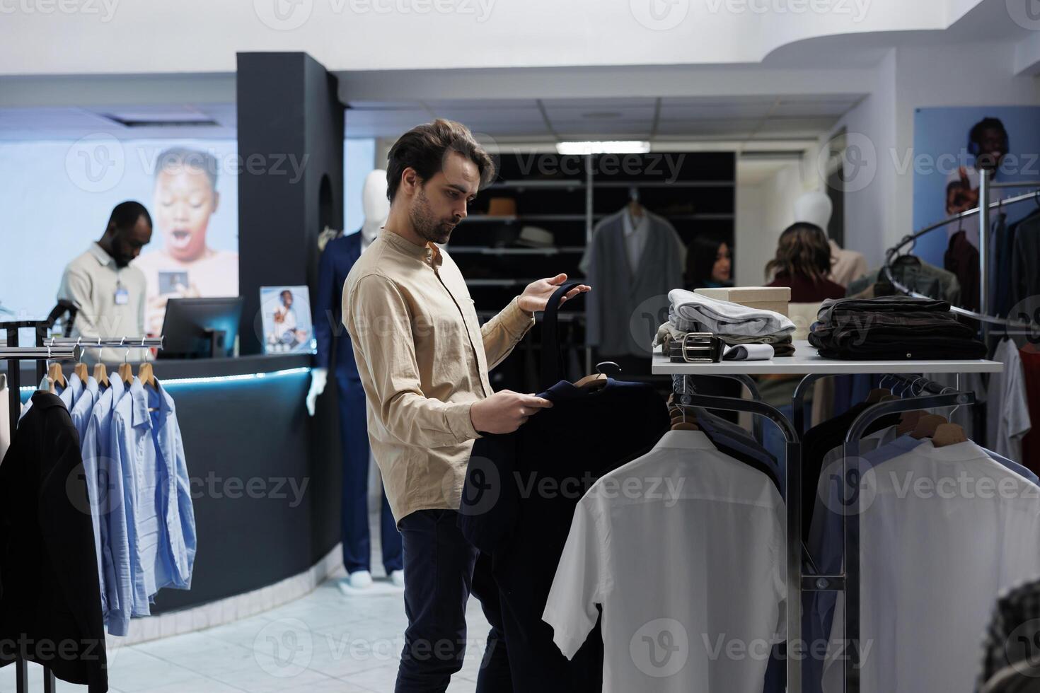 Young caucasian man checking tie and shirt match while choosing formal outfit in clothing store. Customer examining apparel and accessory style while shopping for menswear in boutique photo