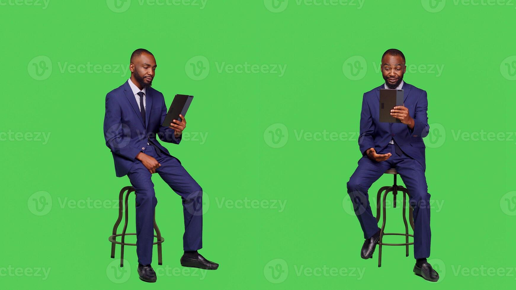 Business manager talking on online videoconference call sitting on chair in studio, full body green screen backdrop. Young entrepreneur using tablet with remote videocall meeting. photo