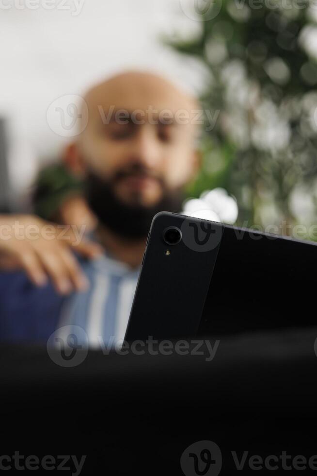 Blurred manager having video conference call using digital tablet, telecommuting with remote workers in office. Business company project manager teleworking with employees photo