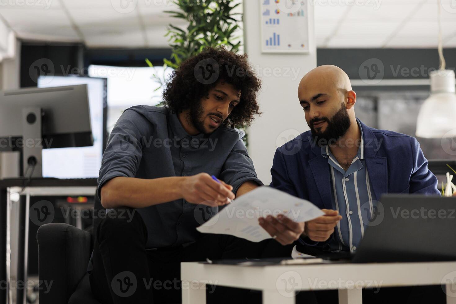 Two startup coworkers collaborating on business plan and analyzing sales report in coworking space. Company employees checking financial analytics and discussing market research photo