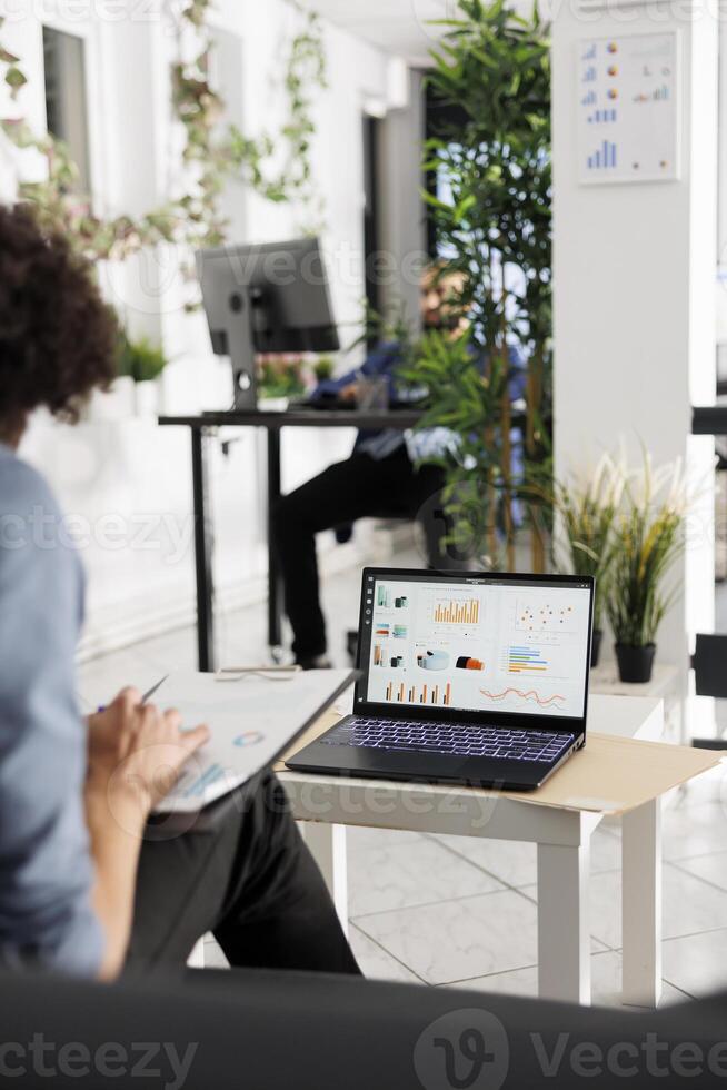 Businessman reviewing sales data and revenue reports on laptop screen in business office. Executive comparing financial statistics and preparing strategy plan for company photo