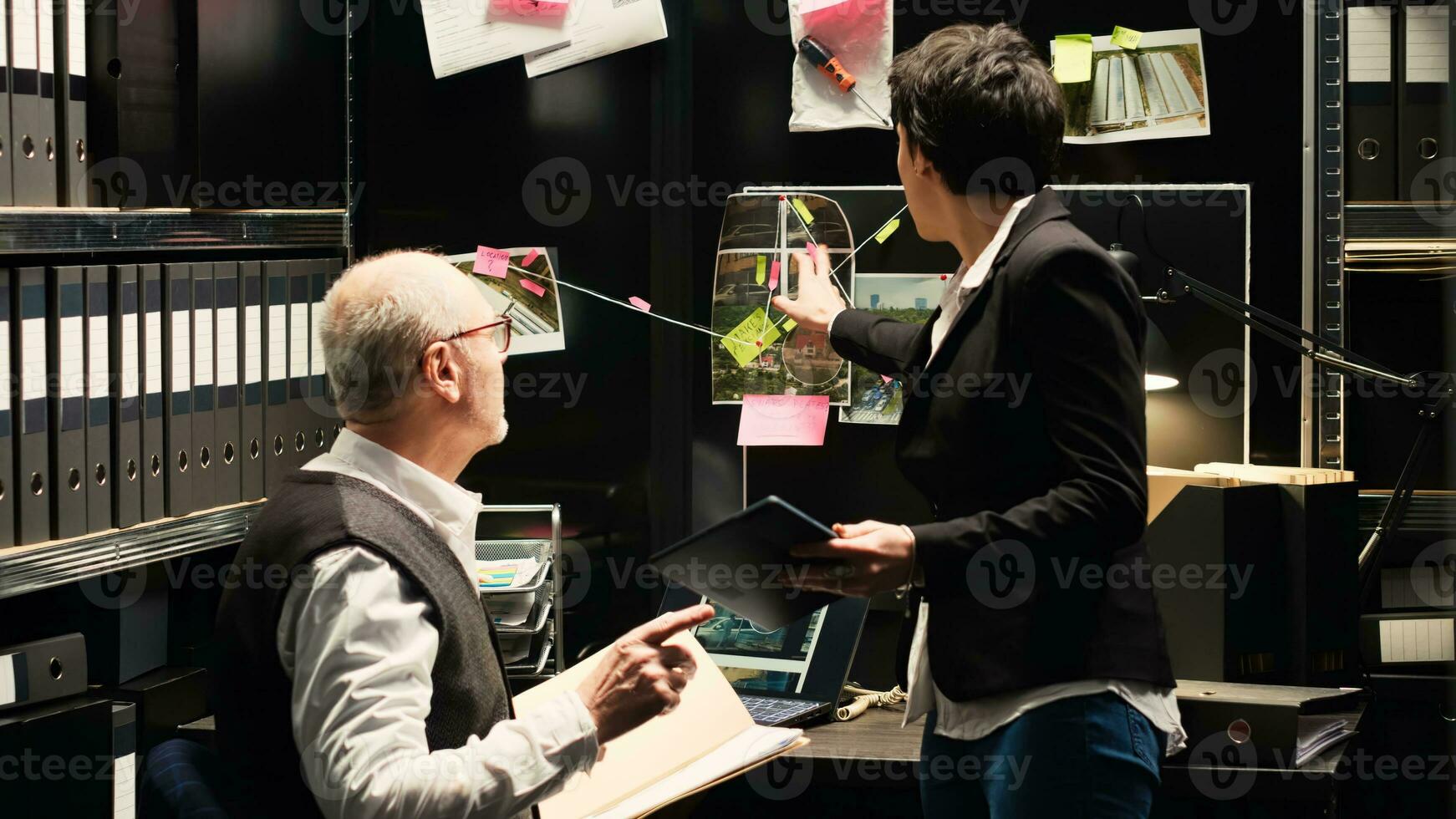 Police experts gathering clues for new criminal mistery in incident room. Detective coworking with law inspector to conduct investigation and solve organized crime case. Handheld shot. photo