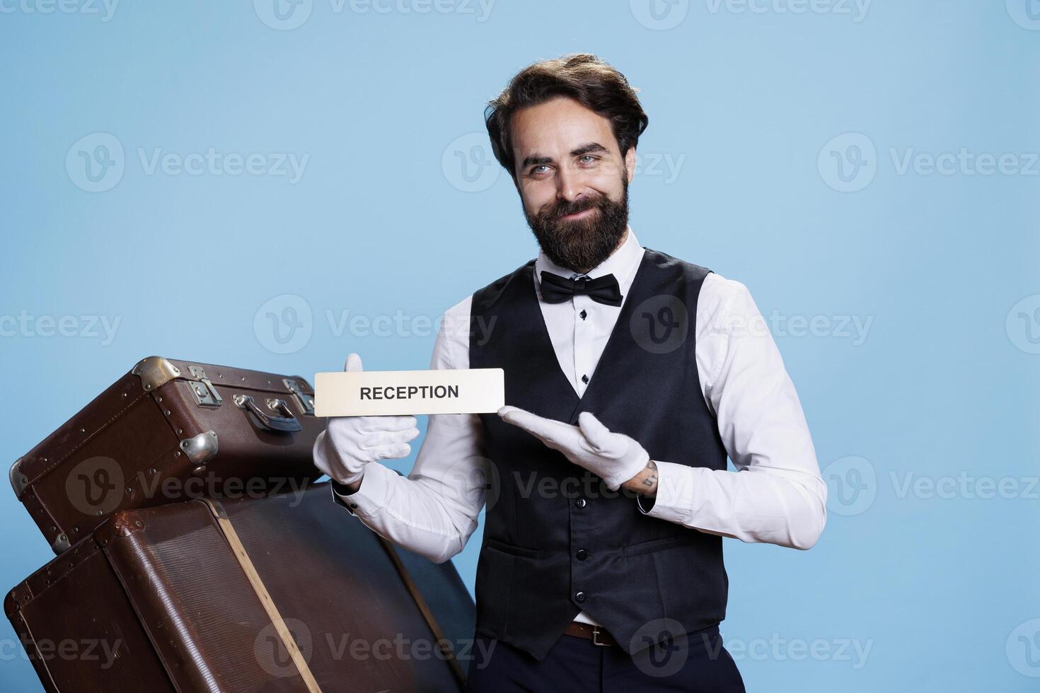 Lodging worker directs people in the proper place using reception indicator. In the hotel industry, elegant doorman employee appears on camera presenting front desk wall sign. photo