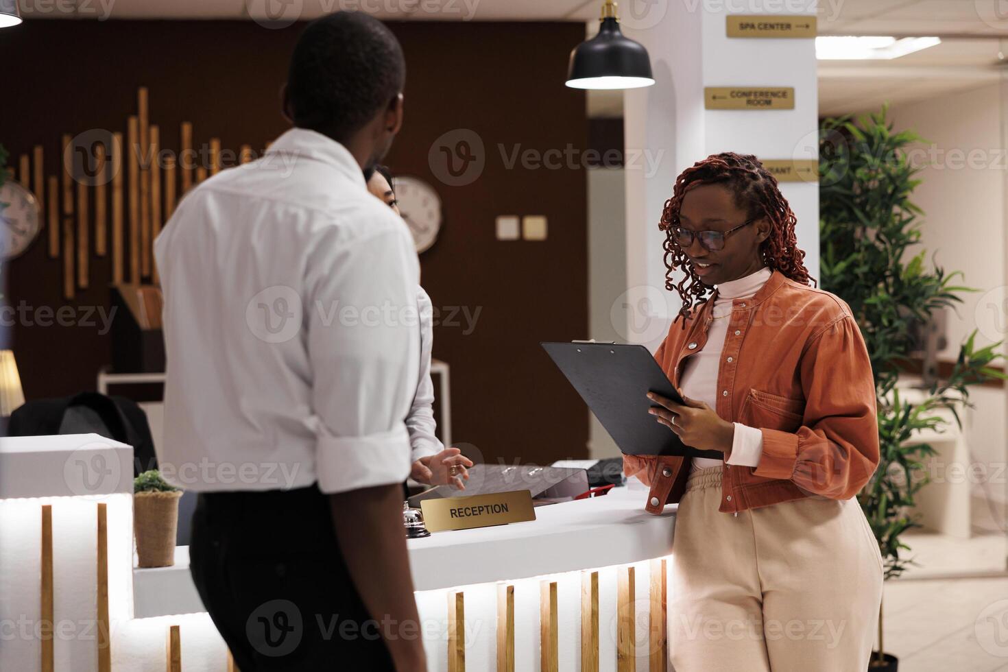 Female guest filling in forms for registration at modern hotel, using tablet to do check in process and review booking details. Young woman arriving at front desk, registering for room. photo