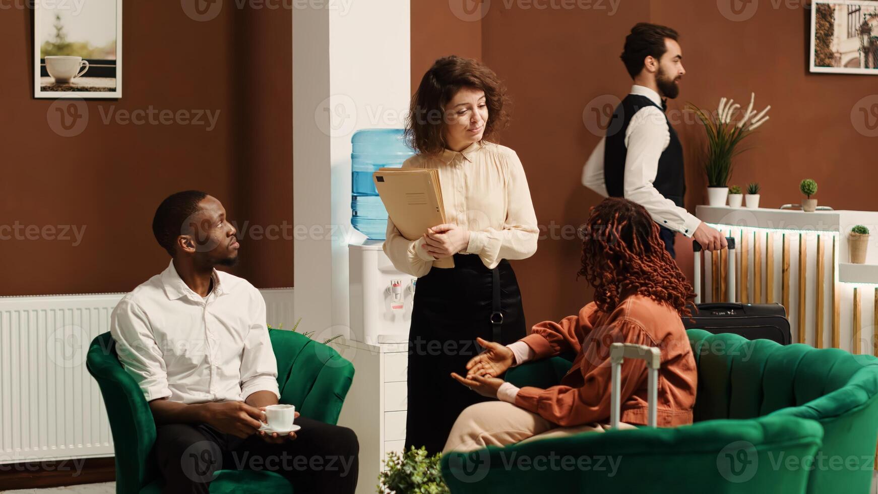 Hospitality manager upselling tourists, suggesting hotel extras and room upgrades, trying to accommodate any special request. Guests discussing booking options while being checked in photo