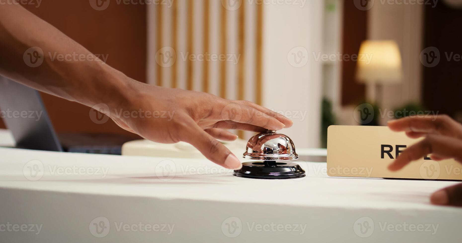 Close up shot of african american tourists ringing service bell at reception counter during booking process. Vacation trip tourists ready to check in at hotel lounge front desk photo
