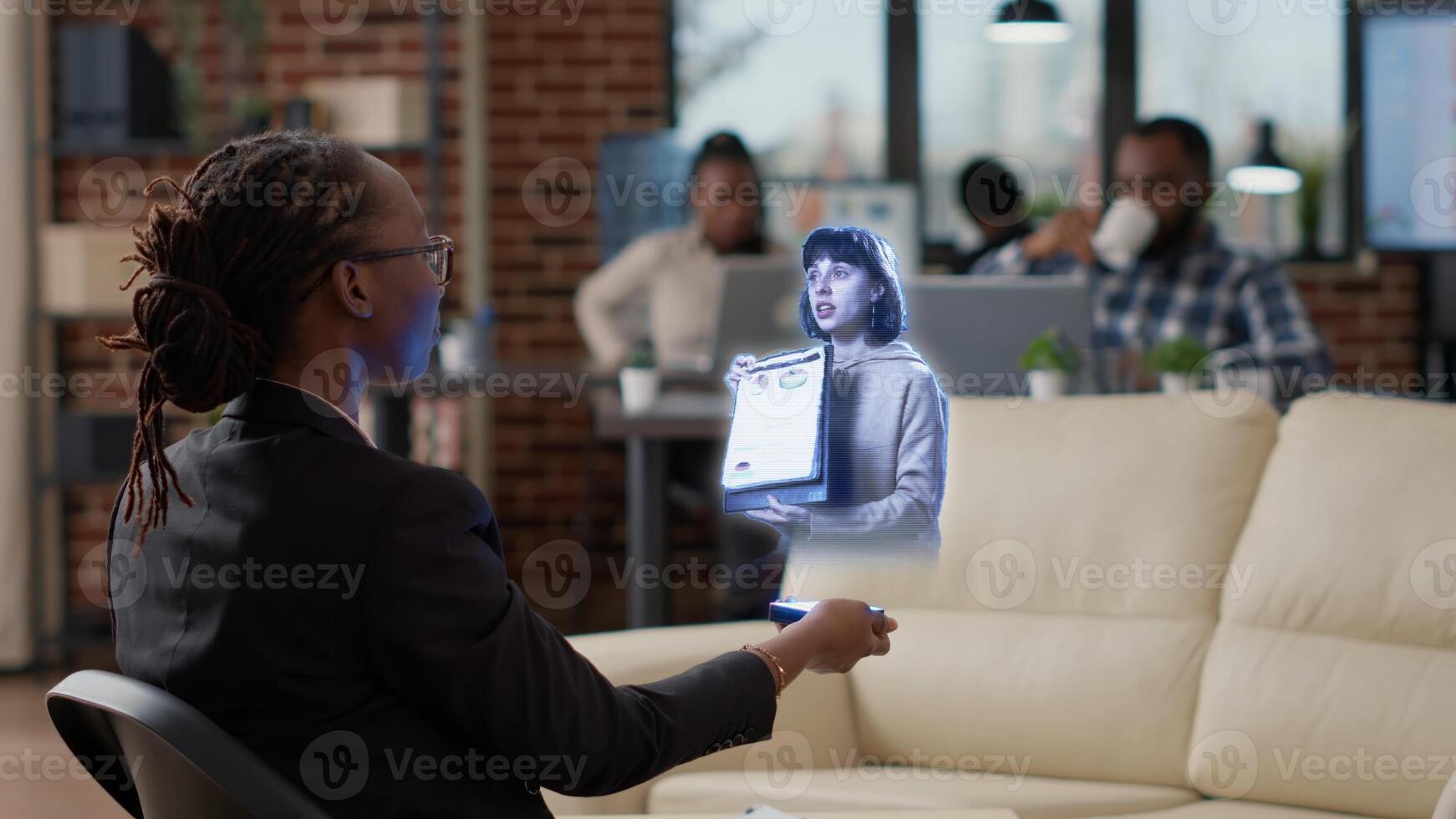 Team leader AR teleconference meeting, in high tech office talking with african american worker in . Businesswoman at workplace desk in online holographic videocall with manager photo