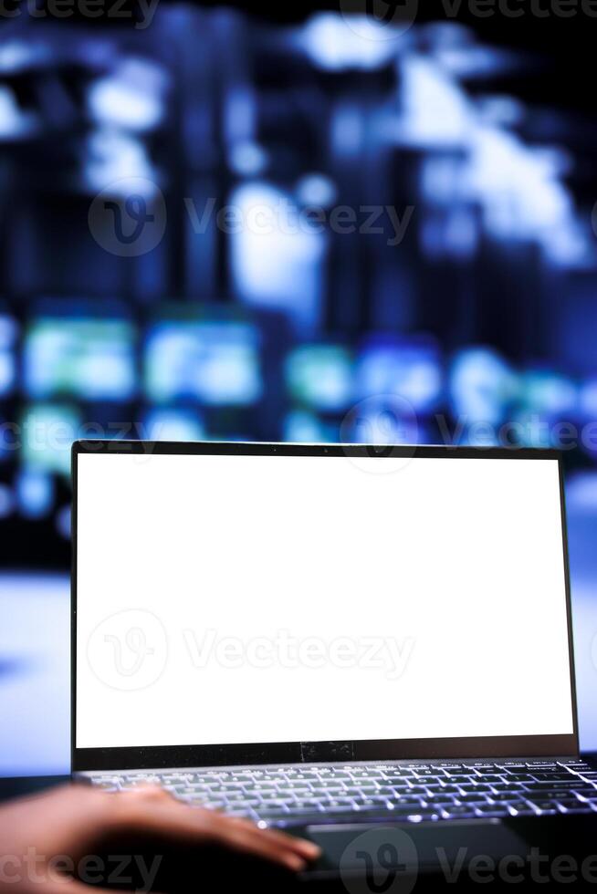 Employee using mock up laptop to audit server mainframes with high computing power, enabling data center to support demanding applications such as machine learning and 3D rendering workloads, close up photo