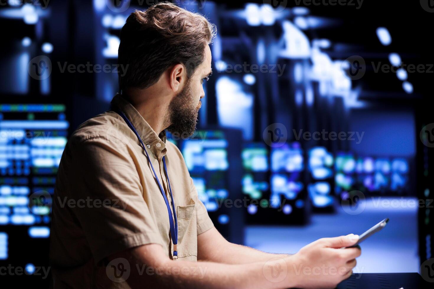 Qualified computer scientist resolving performance related issues in server rows. Programmer utilizing tablet to identify operational problems causing high tech establishment hardware slowdown photo