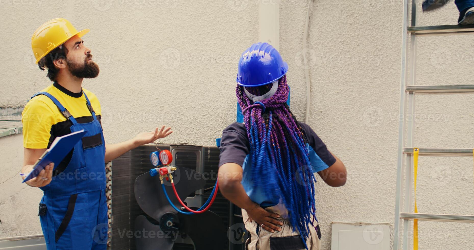 Precise servicemen working with pressure indicators to check condenser refrigerant levels, writing result on clipboard. Proficient experts using barometer benchmarking air conditioner tool photo