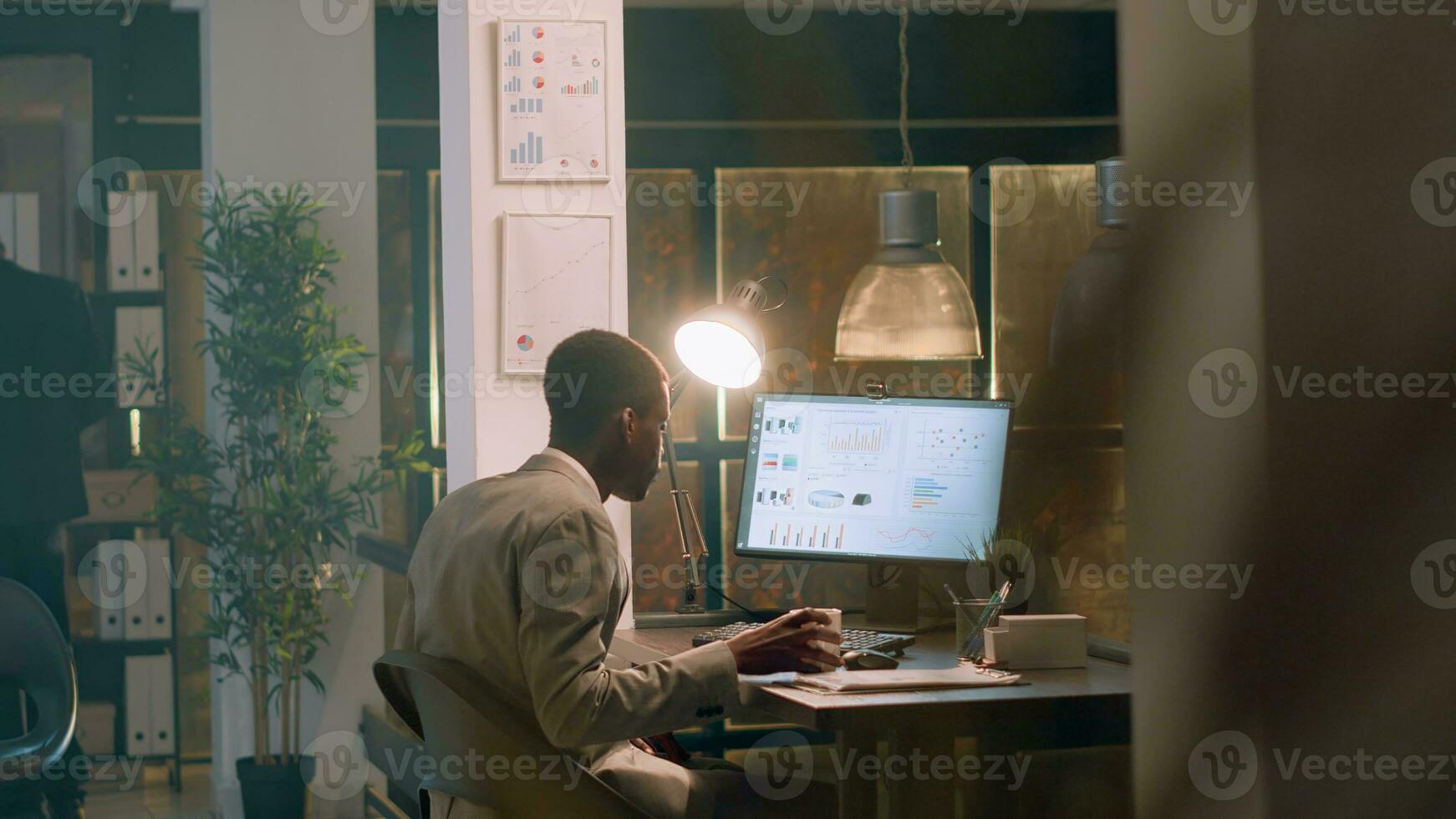 Employee enjoying cup of coffee while imputing financial datasets on computer during nightshift, helped by supervisor. Accountant working in office under manager guidance photo