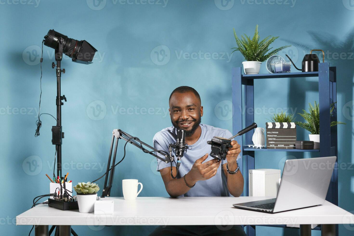 blogger demostración trípode fluido cabeza características, revisando fotografía profesional equipo. sonriente Internet hombre de influencia promoviendo y recomendando cámara engranaje mientras En Vivo transmisión foto