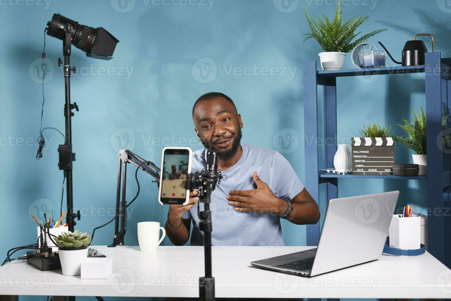 Blogger speaking in microphone and filming video for internet channel using smartphone. Internet vlogger streaming on social media with mobile phone, creating content for vlog photo