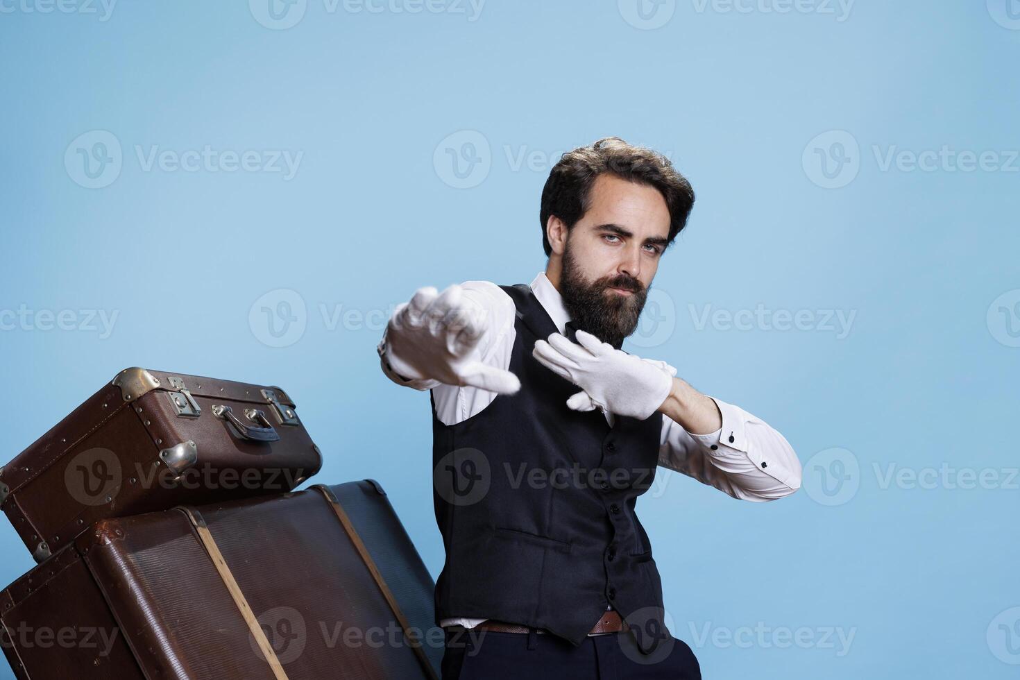 Groovy male bellhop dancing on camera, feeling happy and confident with silly dance moves in formal attire. Young professional doorman acting funky and fooling around in studio. photo