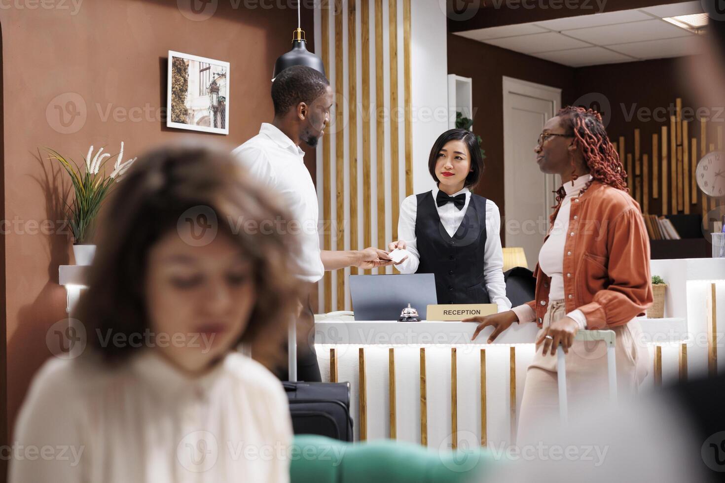 Guests receiving key card at front desk, doing check in process and preparing to register for hotel room access. Receptionist helping tourists with access control at front desk, welcome people. photo