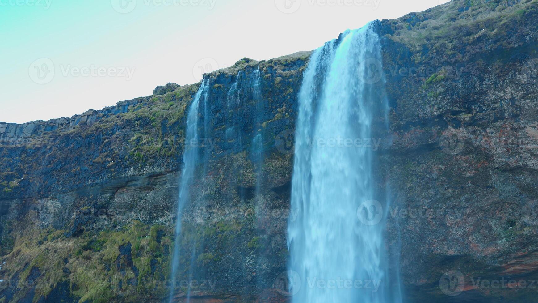 Beautiful waterfall in reykjavik iceland with water flowing off cliffs and hills, seljalandsfoss cascade with river stream. Majestic icelandic landscapes and wilderness, spectacular scenery. photo