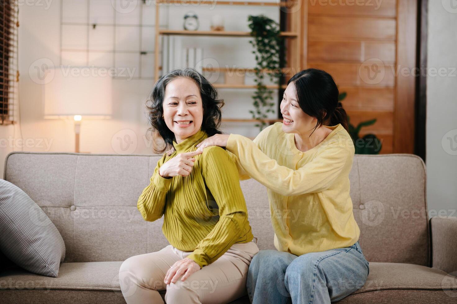 Happy adult granddaughter and senior grandmother having fun enjoying talk sit on sofa in modern living room, using a laptop, tablet bonding chatting relaxing at home together photo
