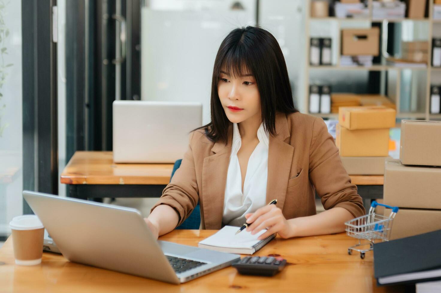Successful Asian Businesswoman Analyzing Finance on Tablet and Laptop at Office Desk tax, report, accounting, statistics, and analytical research concept photo