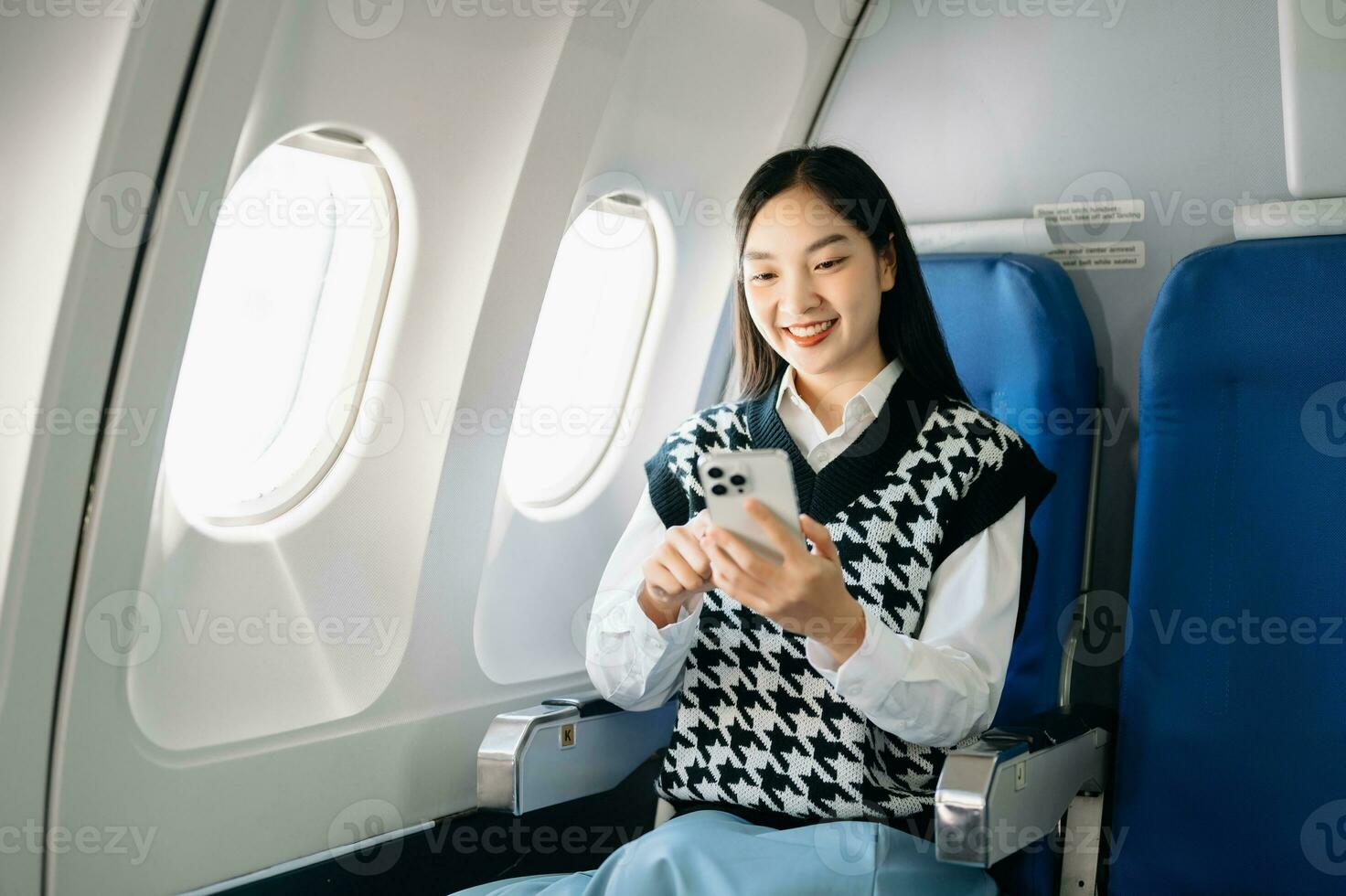Young Asian executive excels in first class, multitasking with digital tablet, laptop and smartphone. Travel in style, work with grace. photo