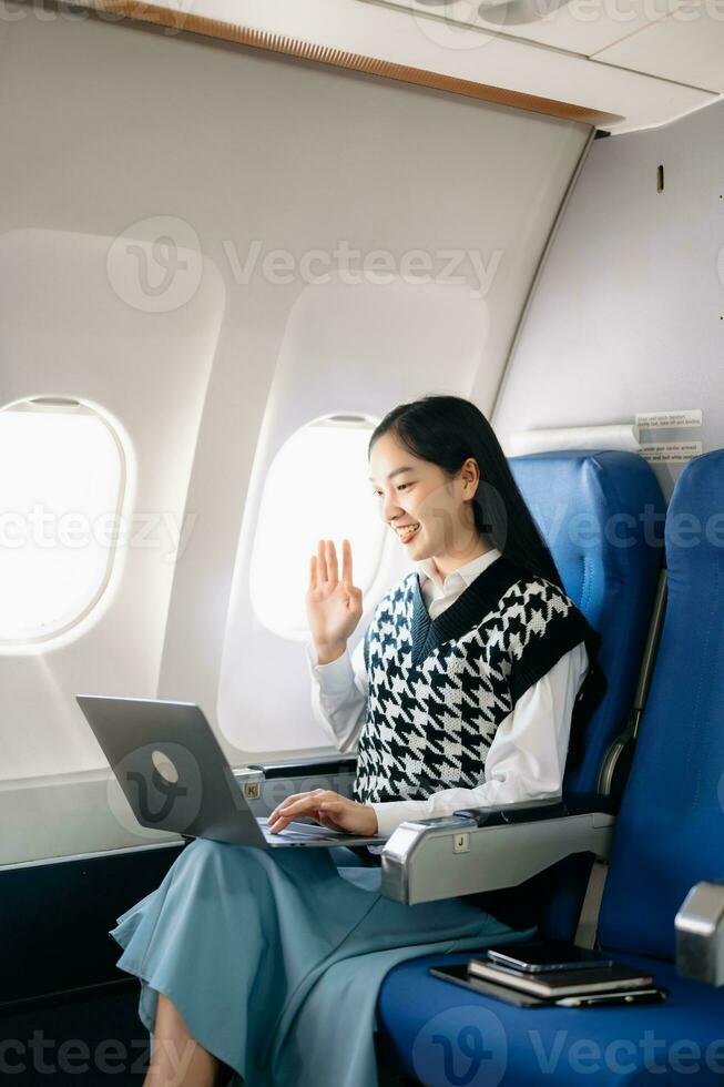 Young Asian executive excels in first class, multitasking with digital tablet, laptop and smartphone. Travel in style, work with grace. in morning light photo