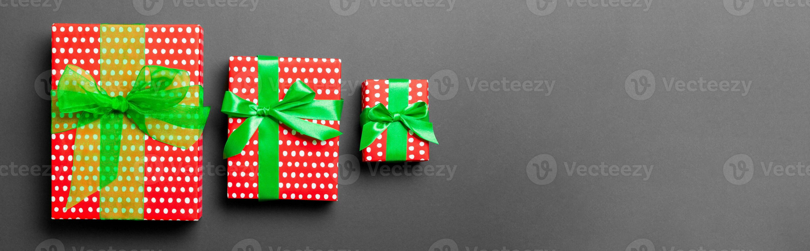 Top view Christmas present box with green bow on black background